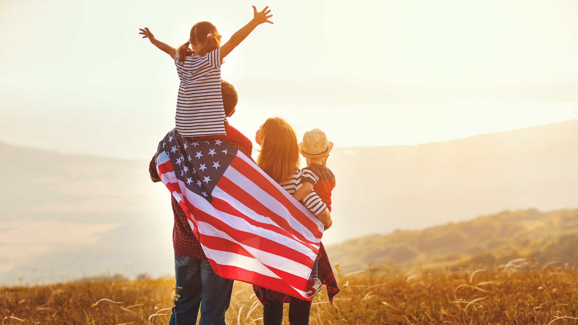 Happy,Family,With,The,Flag,Of,America,Usa,At,Sunset